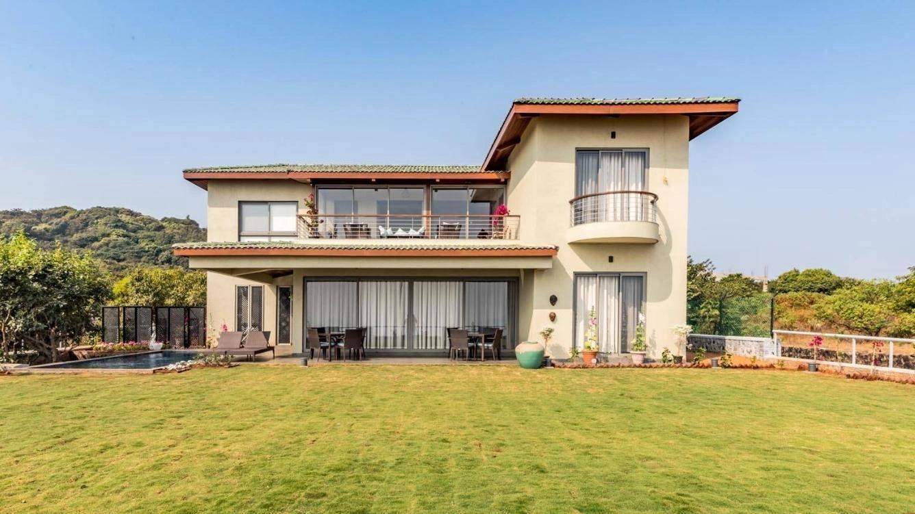 Spacious two-story villa with a green lawn and mountain backdrop at Ramsukh Resort.